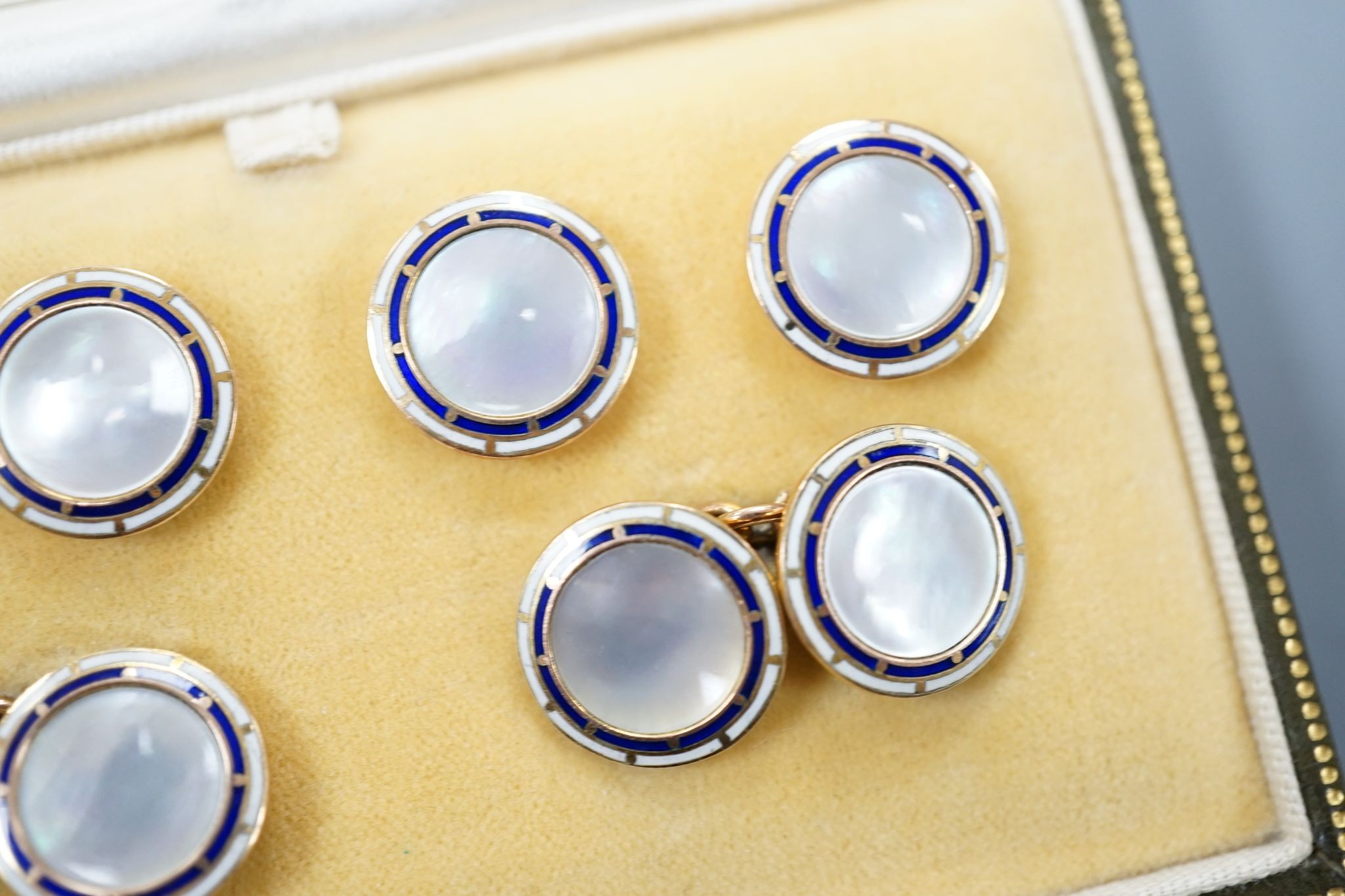 A cased 9ct, mother of pearl and enamel set six piece dress stud set, gross set 10.3 grams